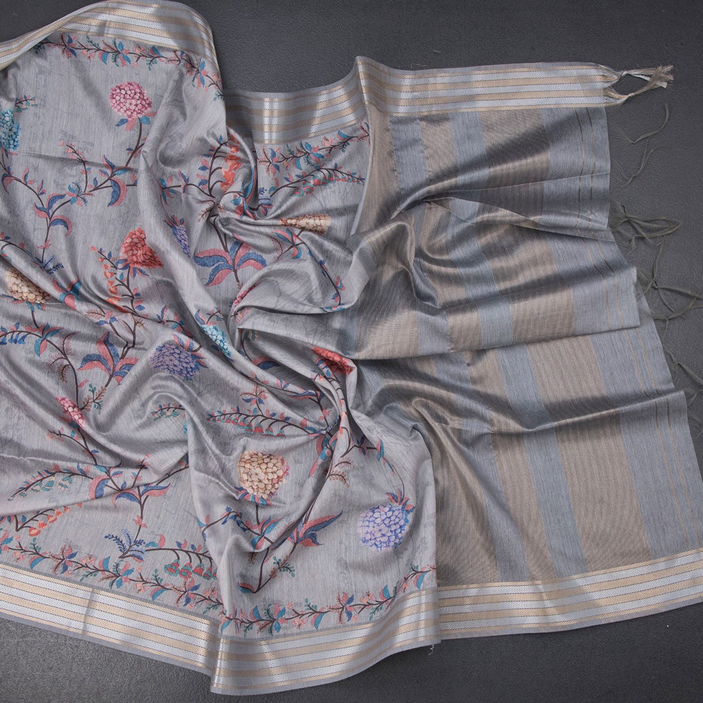 Light grey raw silk saree with floral print and zari border from Shriyara Life, showcasing intricate fabric details and elegant design.