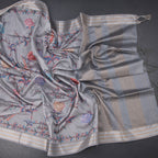 Light grey raw silk saree with floral print and zari border from Shriyara Life, showcasing intricate fabric details and elegant design.