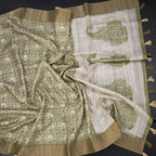 Green raw silk saree with printed design and zari border from Shriyara Life, featuring intricate weaving and vibrant traditional patterns.